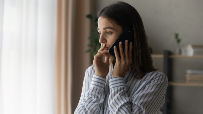 A woman feeling stressed while talking on the phone.