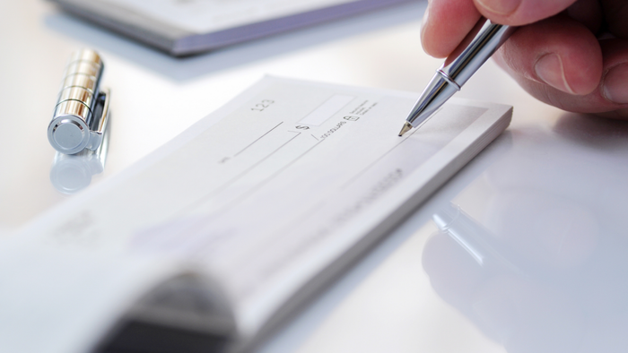 A detailed image of an individual writing a check using a high-end pen