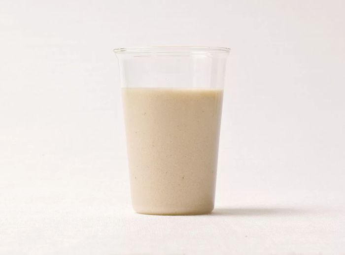 A banana-cashew smoothie served in a plastic cup.