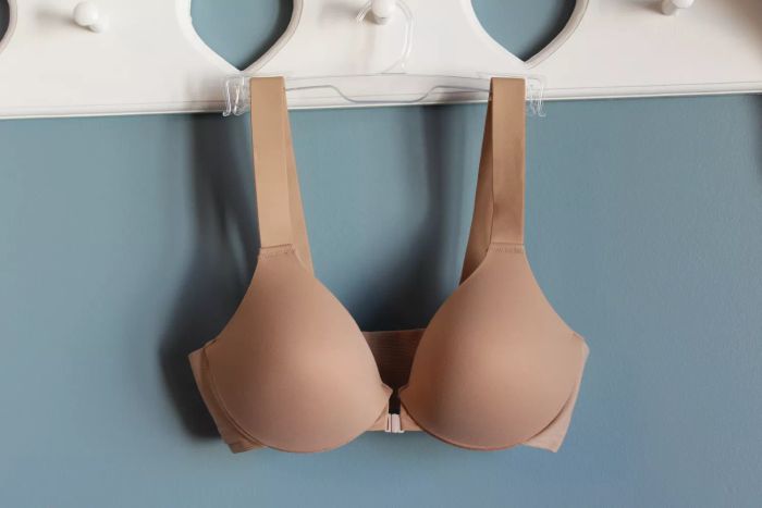 The Spanx Bra-llelujah! Lightly Lined Wireless Bra hanging on a hanger against a blue wall.