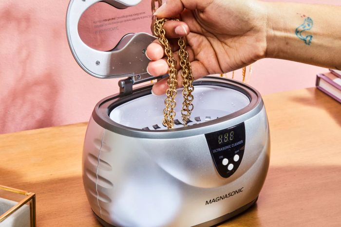 Someone placing a necklace into the Magnasonic Ultrasonic Jewelry Cleaner