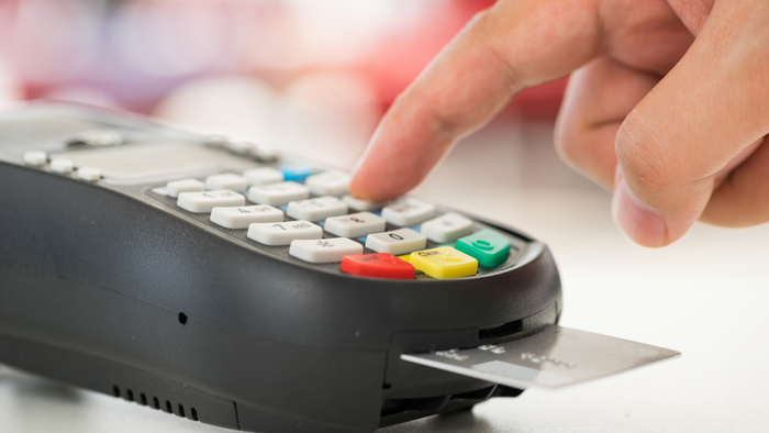 A credit card being inserted into a chip-enabled reader.
