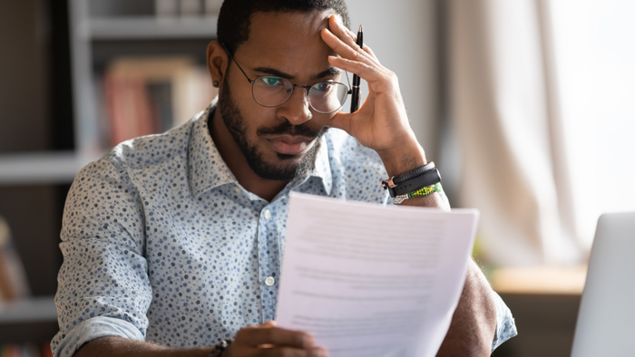 A man frustrated while staring at his financial paperwork