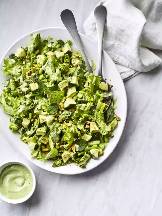 Spring green salad displayed on a serving platter and served with a green dressing.