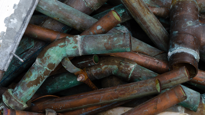 a stack of worn-out, rusty copper pipes