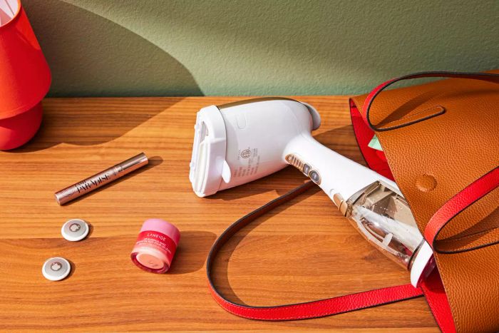 A Conair Handheld Garment Steamer being taken out of a purse and placed on a counter