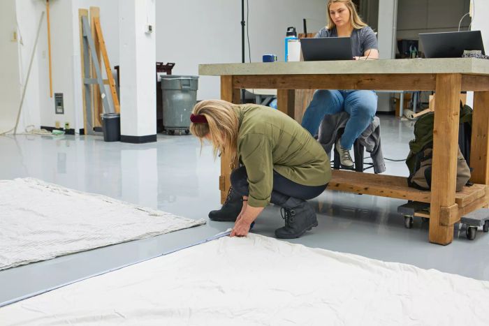 A person measuring The Company Store's Cotton Rayon Bamboo Sateen Duvet Cover with a tape measure on the floor