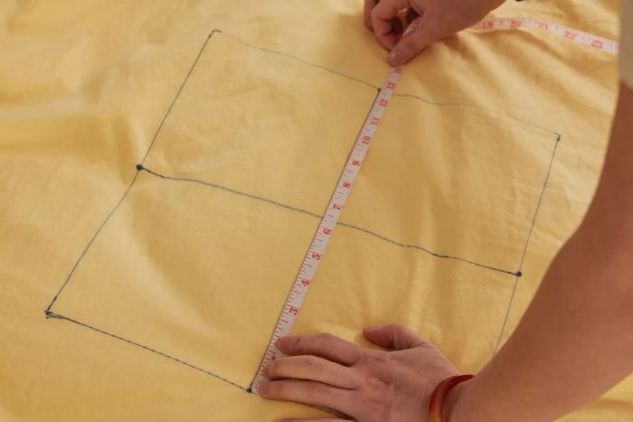 A person measuring a L.L.Bean 280-Thread-Count Pima Cotton Percale Comforter Cover with a tape measure