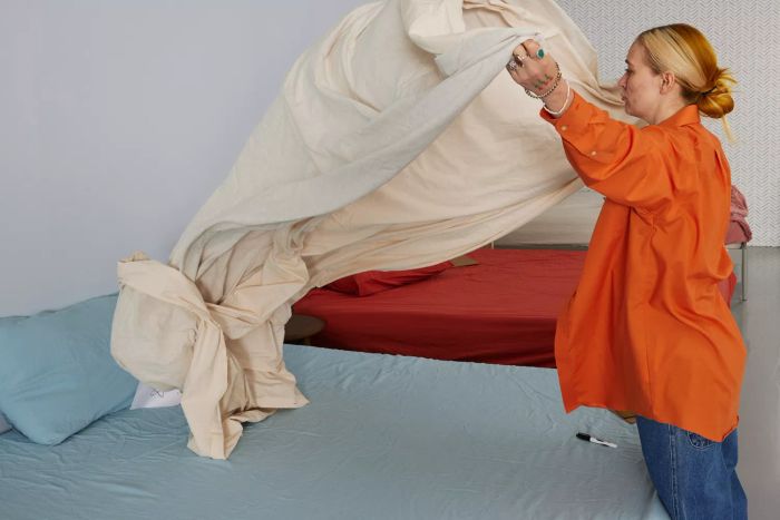 A person is placing the Southern Living Simplicity Collection Tanner Duvet Cover on a bed.