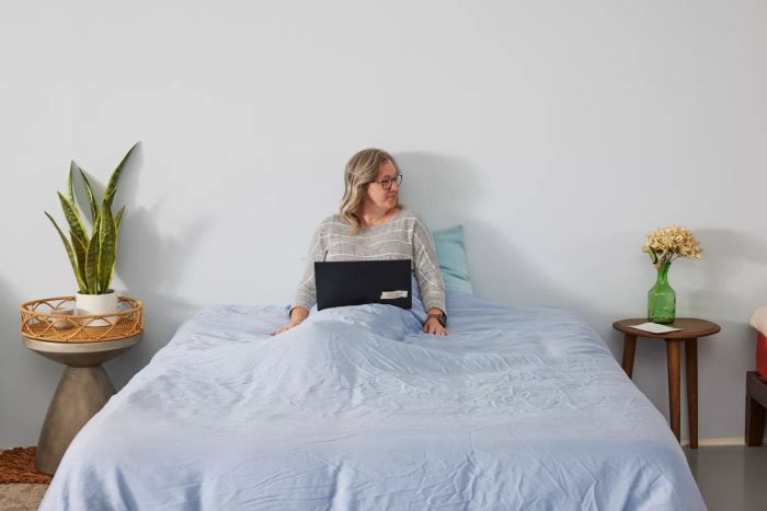 A person relaxing in the Sijo AiryWeight Eucalyptus Duvet Cover with a laptop on their lap