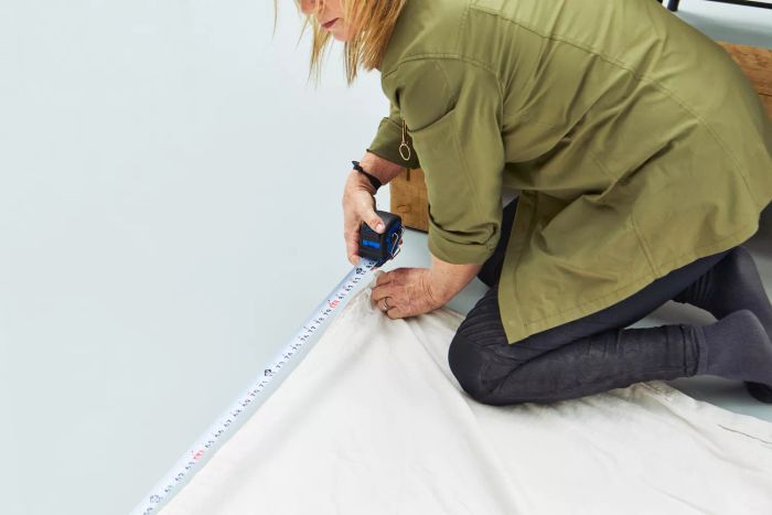 A person measuring the length of The Company Store's Cotton Rayon Bamboo Sateen Duvet Cover with a tape measure on the floor