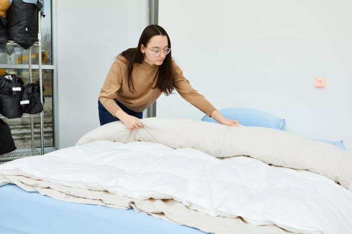 An individual adjusting the Quince European Linen Duvet Cover on a bed