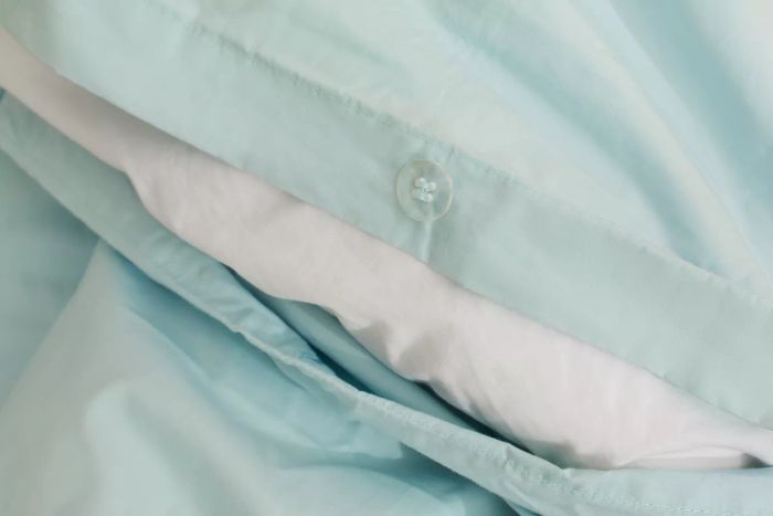 A close-up view of the button closure on the Riley Percale Duvet Cover.