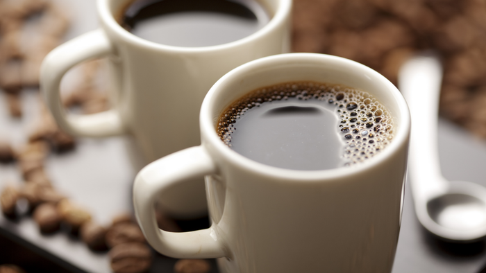 An image of two white mugs filled with black coffee