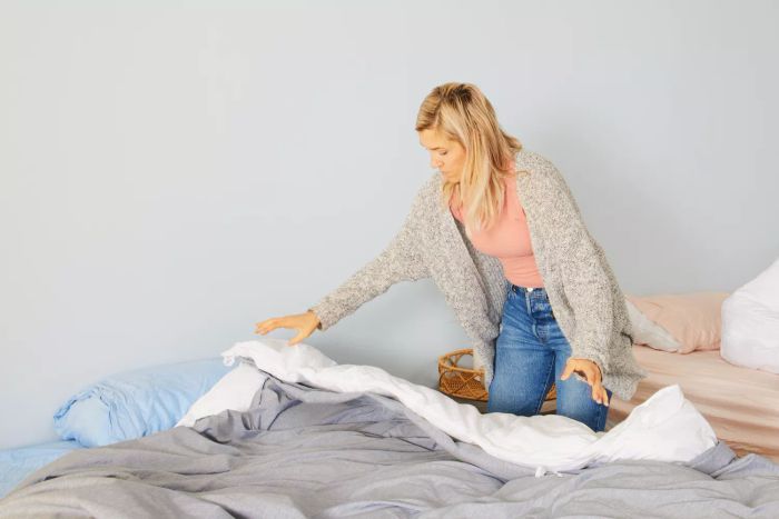 A person carefully inserting a comforter into the Bare Home Duvet Cover.
