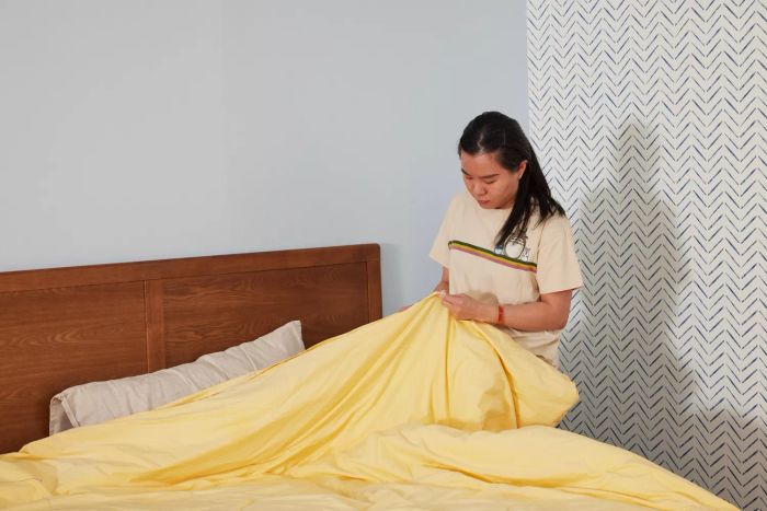 A person touching the fabric of the L.L.Bean 280-Thread-Count Pima Cotton Percale Comforter Cover Collection