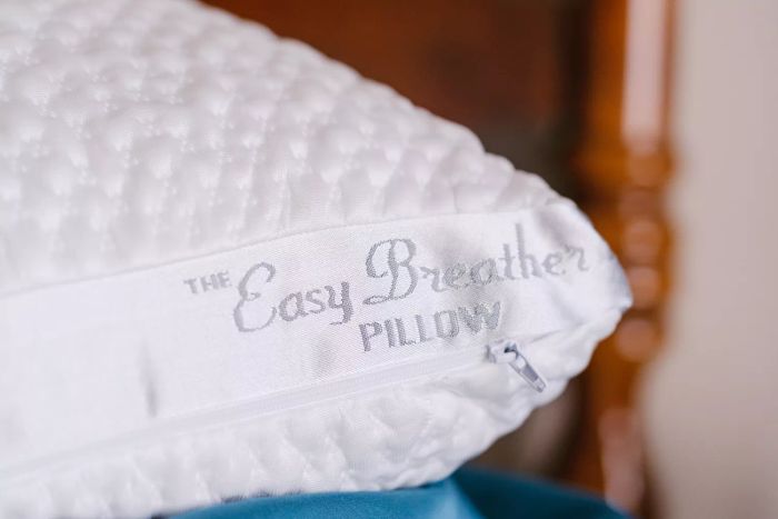 A detailed closeup of the Nest Bedding Easy Breather Natural Pillow's logo and zipper