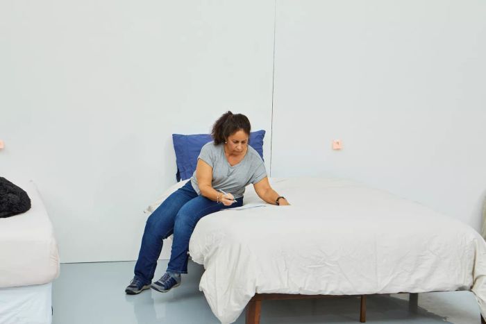 A person is seated on a bed adorned with the Parachute Sateen Duvet Cover, jotting down notes on a sheet of paper