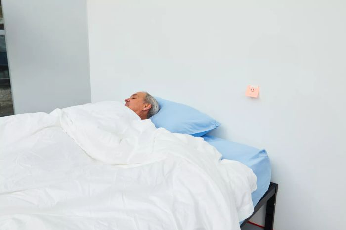 A person peacefully sleeping in a bed adorned with the Boll & Branch Signature Hemmed Duvet Set
