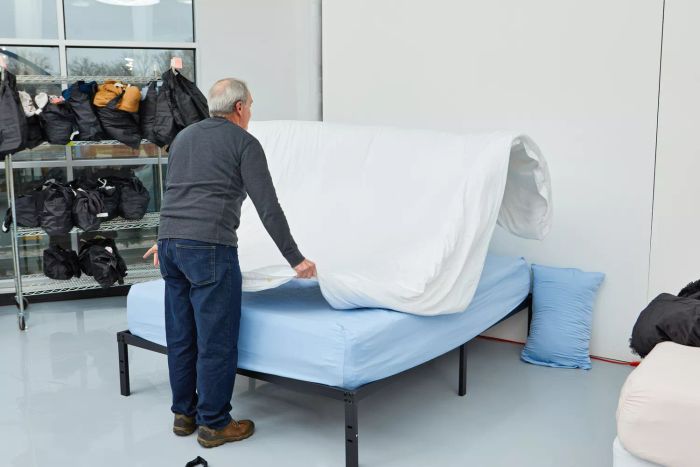 A person carefully dressing a bed with the Boll & Branch Signature Hemmed Duvet Set