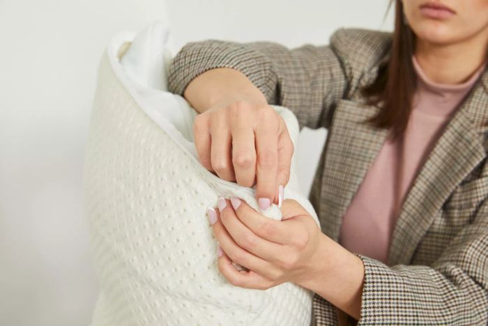 A woman holding the corner of the Snuggle-Pedic Adjustable Shredded Memory Foam Pillow