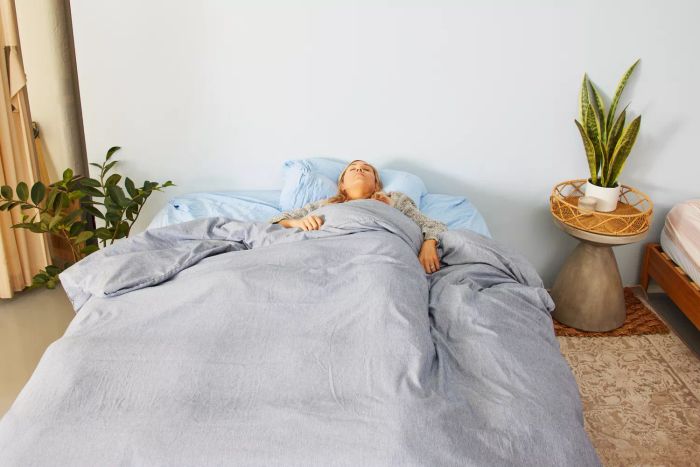 A person comfortably resting on a bed adorned with the Bare Home Duvet Cover.