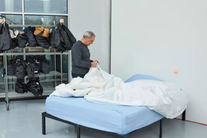 A person neatly arranging the Boll & Branch Signature Hemmed Duvet Set on a bed