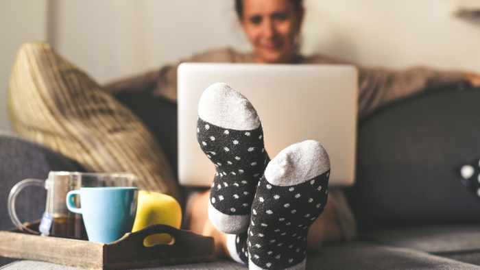 A woman relaxing on a couch in the living room, working on her laptop
