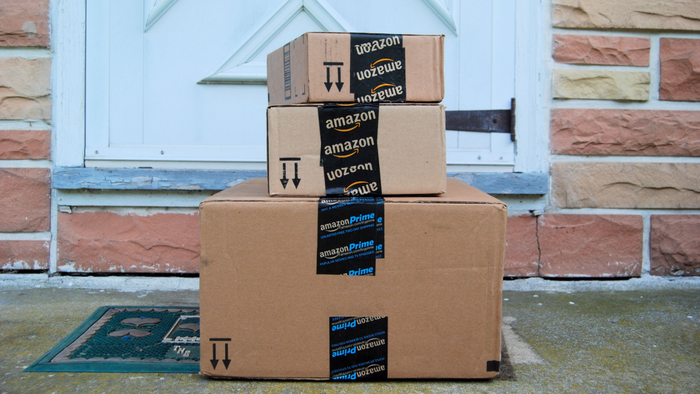 Three Amazon Prime packages stacked on a front porch outside a house.
