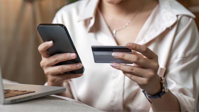 A woman reviewing her credit card and making a phone call for assistance