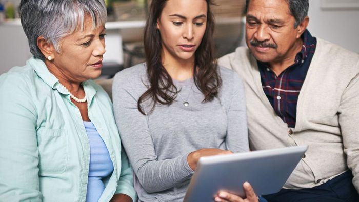 Two older parents following along as their daughter demonstrates something on a tablet