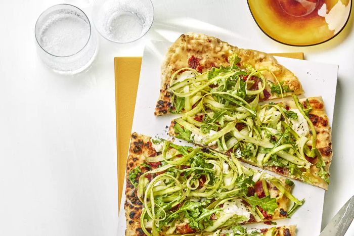 A grilled flatbread topped with savory asparagus, indulgent burrata, and crispy bacon delivers a deliciously satisfying bite.