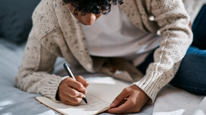 A person writing down their new year's resolutions in a journal.