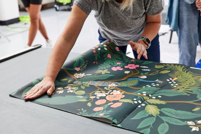 A woman arranging Rifle Paper Co. Peacock Wallpaper on a tabletop