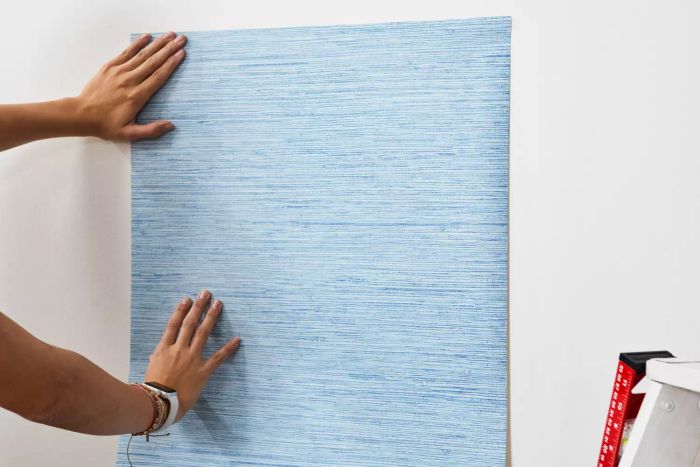 Hands holding York Wallcoverings Nautical Living Wallpaper against a white wall.