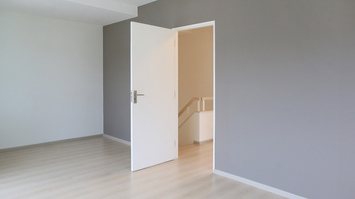 A gray-painted wall featuring an open doorway that leads to a staircase