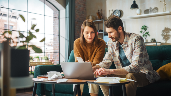 Couple in an apartment working together on their laptop.