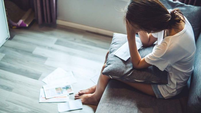 A woman overwhelmed by a mountain of bills
