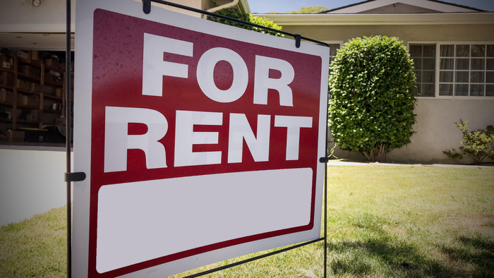 A 'For Rent' sign in front of a house