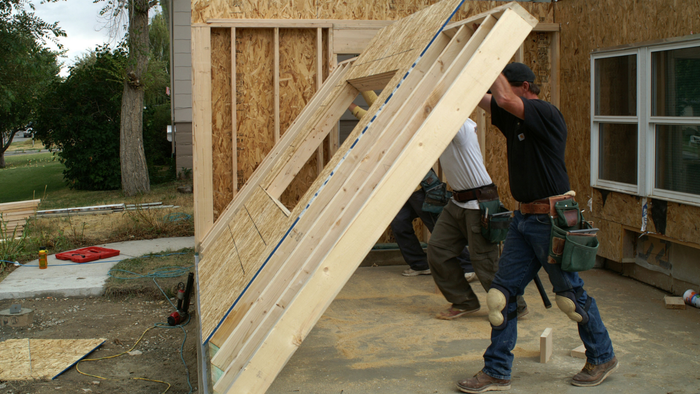 An image showing construction workers erecting the frame for a new wall during a home addition project.