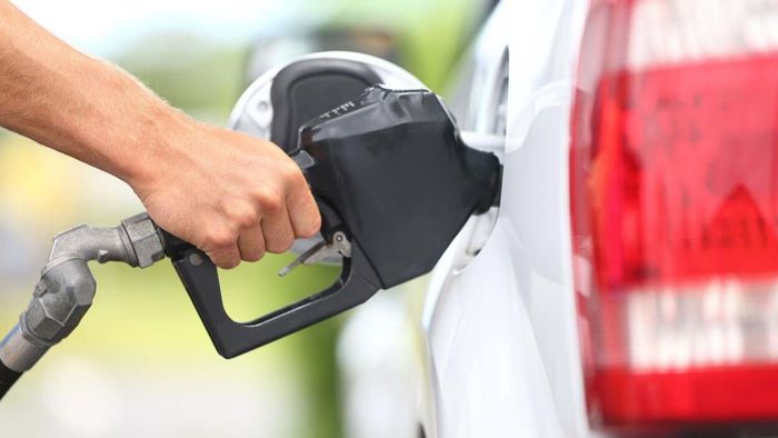 An individual refueling a white car at a gas station