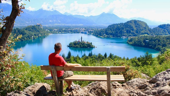 A person gazing out at a vast landscape while seated on a bench