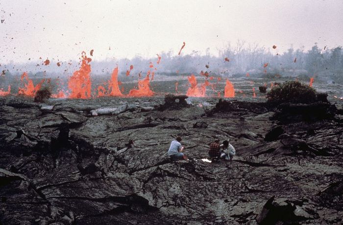 scientists standing before a flowing lava stream