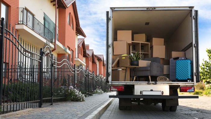 A moving truck partially loaded with belongings is parked in front of a residential building