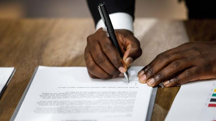 Man in formal attire signing a rental agreement