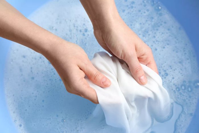 hands soaking a garment in a laundry tub