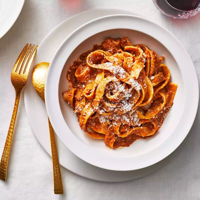Walnut Mushroom Bolognese Pasta served in a white bowl with a bronze fork and spoon placed to its left