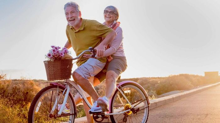 An elderly couple enjoying a bicycle ride side by side.