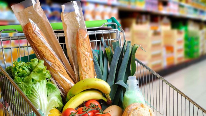 A shopping basket filled with fresh bread and vegetables