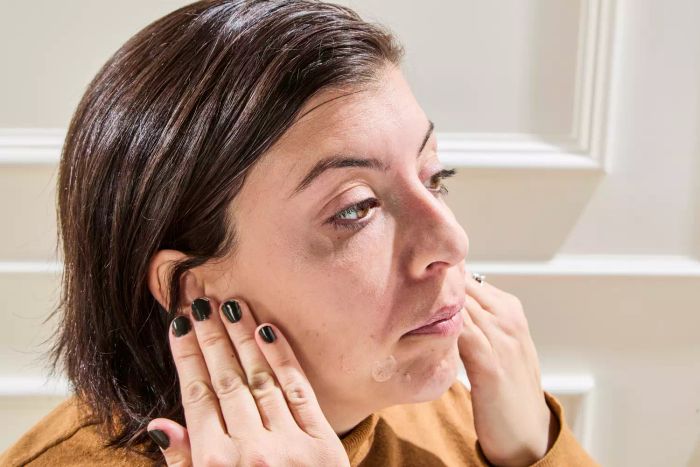 A person blends Tower 28 SunnyDays SPF 30 Tinted Sunscreen onto their face